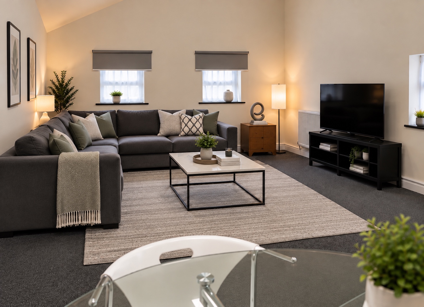 Living room with a grey corner sofa, neutral cushions and warm lighting